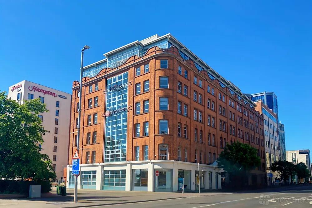 A red brick building with large glass windows and corner signage at Regus - Great Victoria Street.