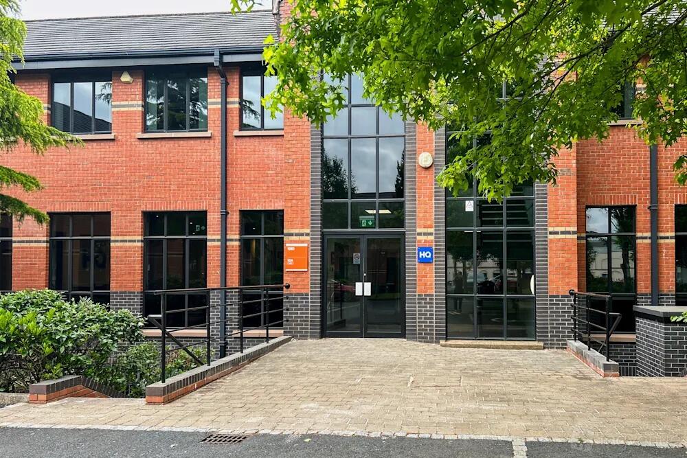 A red brick building with large windows and a paved entrance at Regus - Weavers Court.