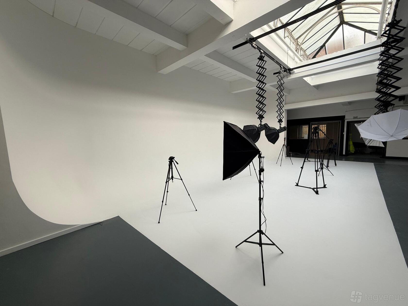 A photo studio with a white cyclorama wall, softbox lighting, and tripod stands at Coles Green Studios.
