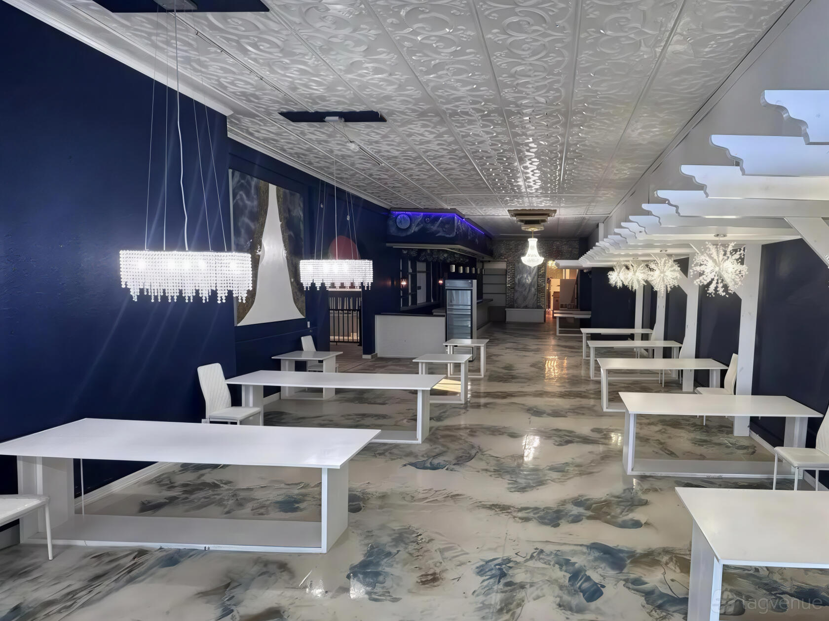 An event venue with white tables, blue walls, decorative chandeliers, and a marbled floor at Pop Up SMTX.