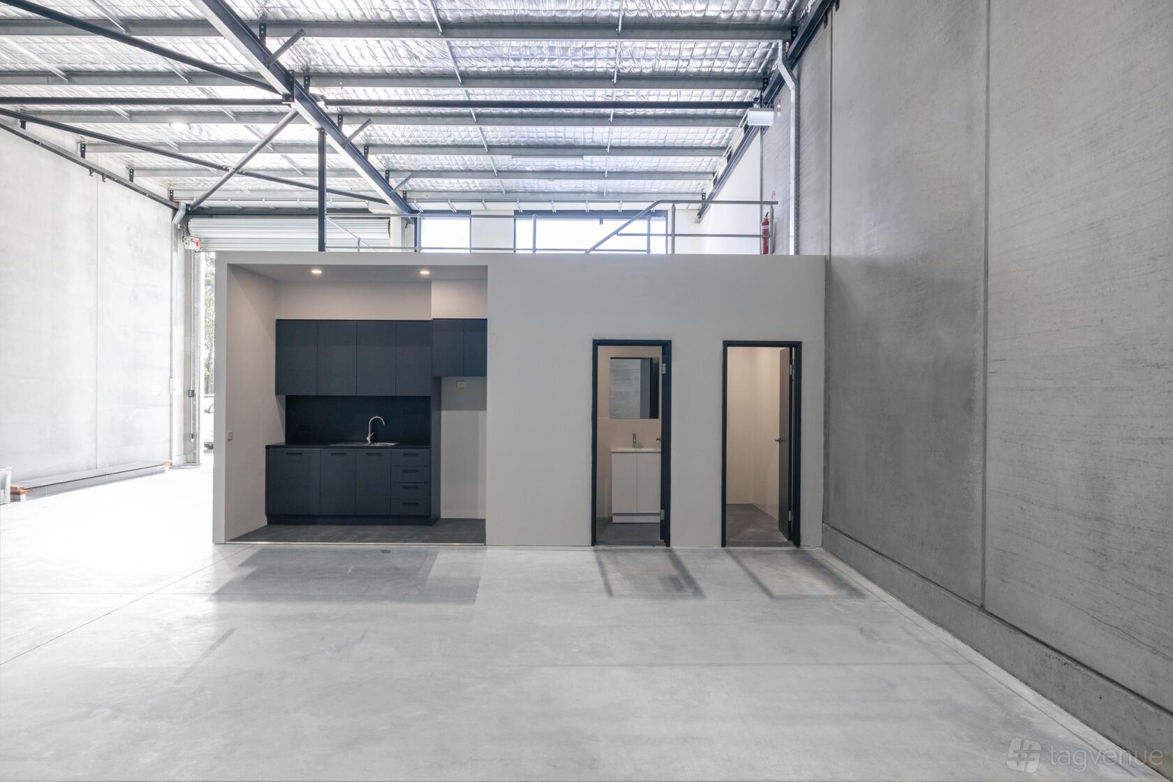 A warehouse with a kitchenette, dark cabinets, and two adjacent office rooms at Nowra Business Park.