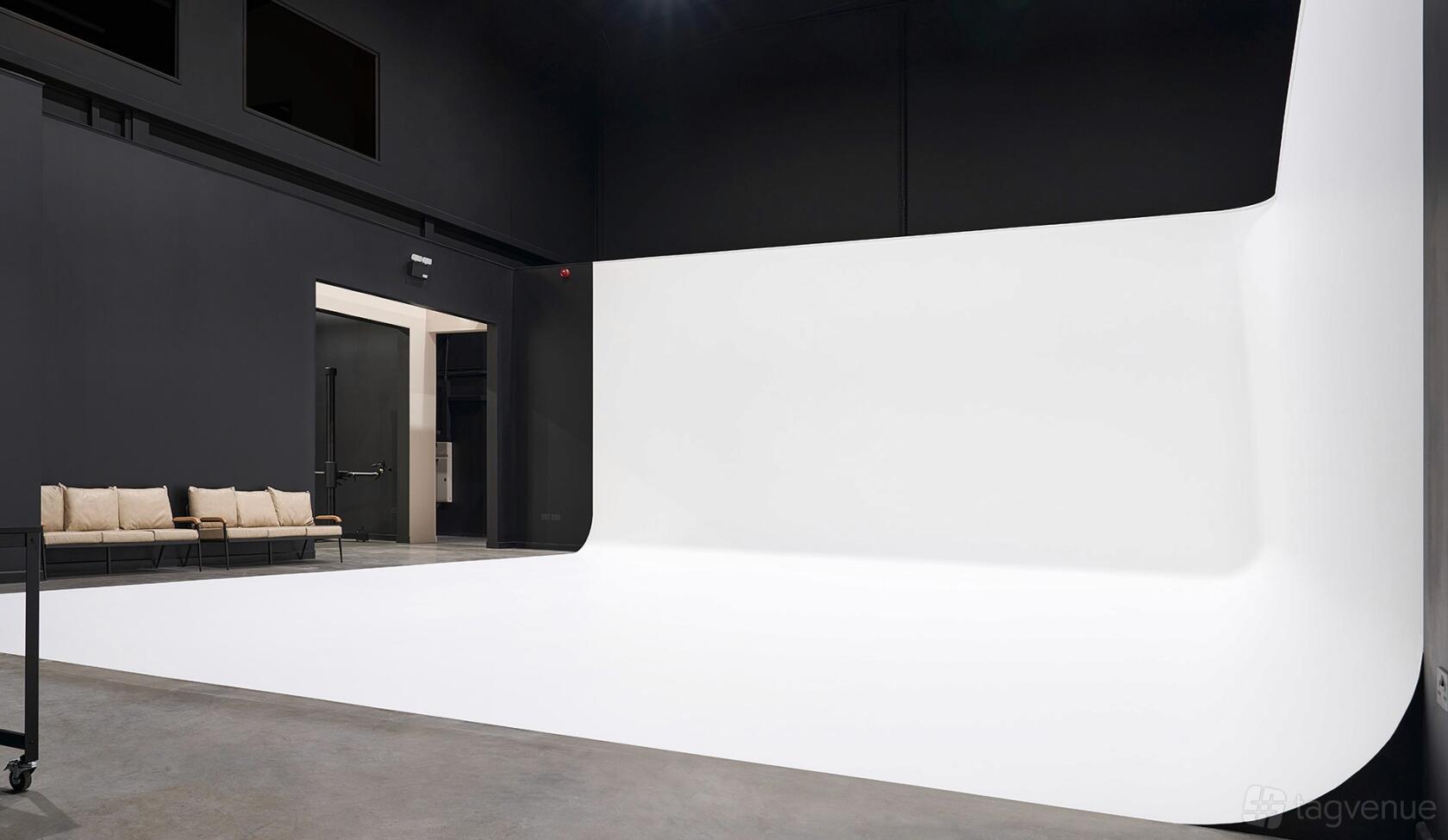 A photo studio with a large white cyclorama wall and concrete floors at Arwec Studios.