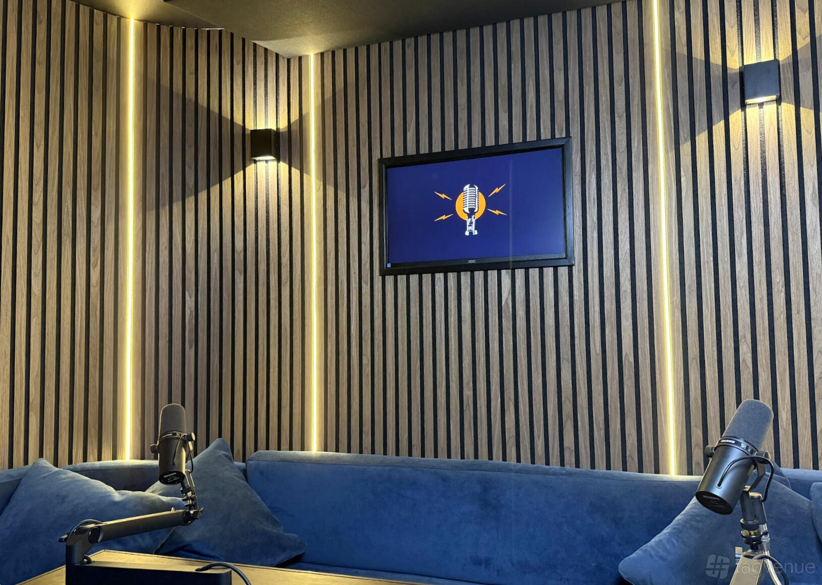 A podcast studio with wall-mounted microphones, wooden slat walls, and a TV screen at Westminster Podcast Studio.