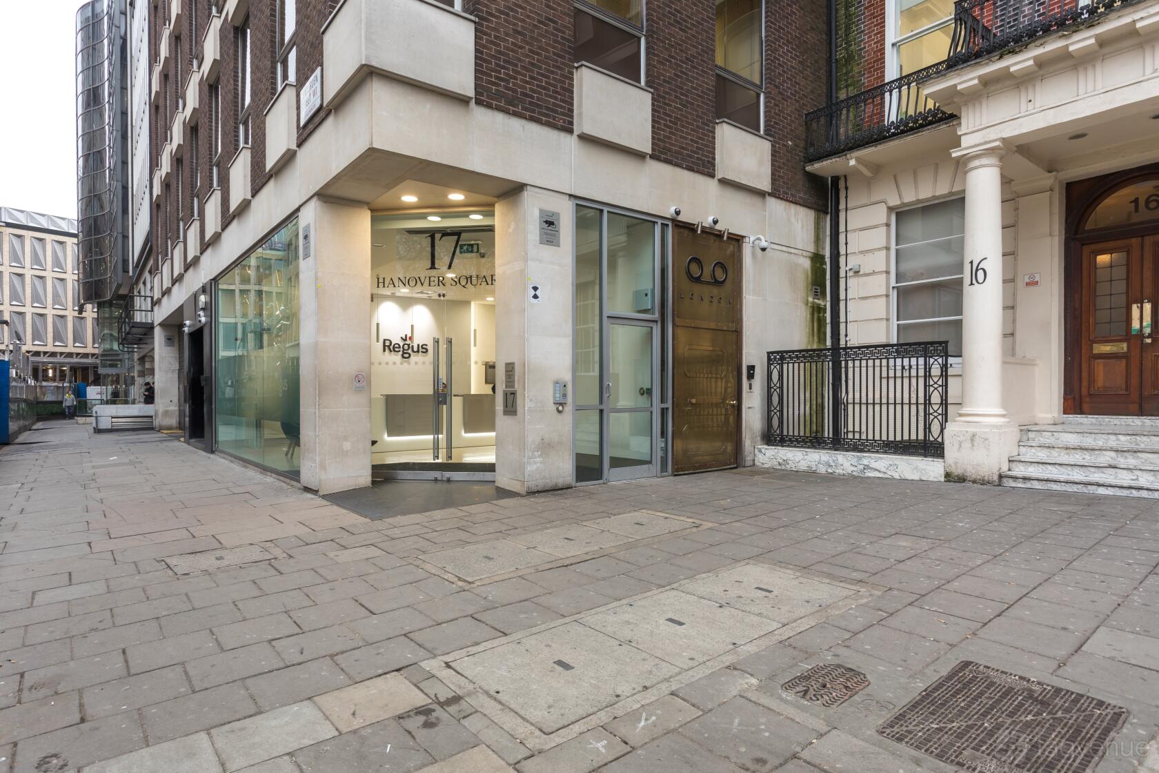 A meeting centre entrance with large glass windows, signage, and a paved walkway at Regus - London, Hanover Square - No 17.