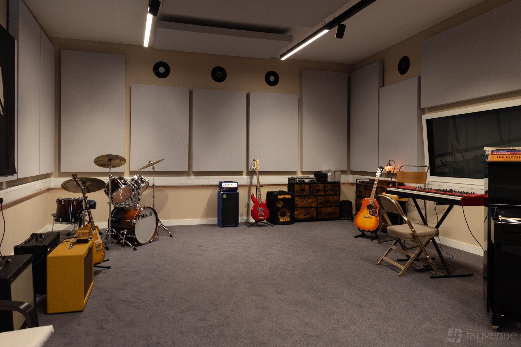 A music studio with acoustic wall panels, drum kit, guitars, keyboard, and amplifiers at Meridian Sound Studios.