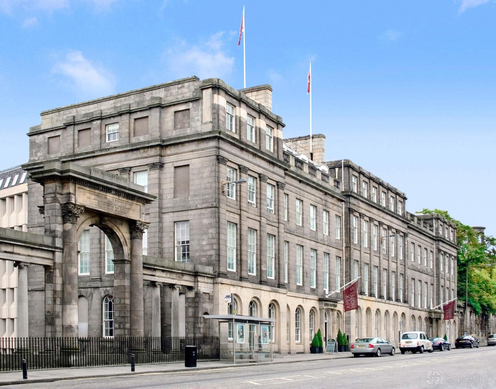 A historic stone hotel with arched windows, flagpoles on the roof, and a grand entrance at Apex Waterloo Place Hotel.