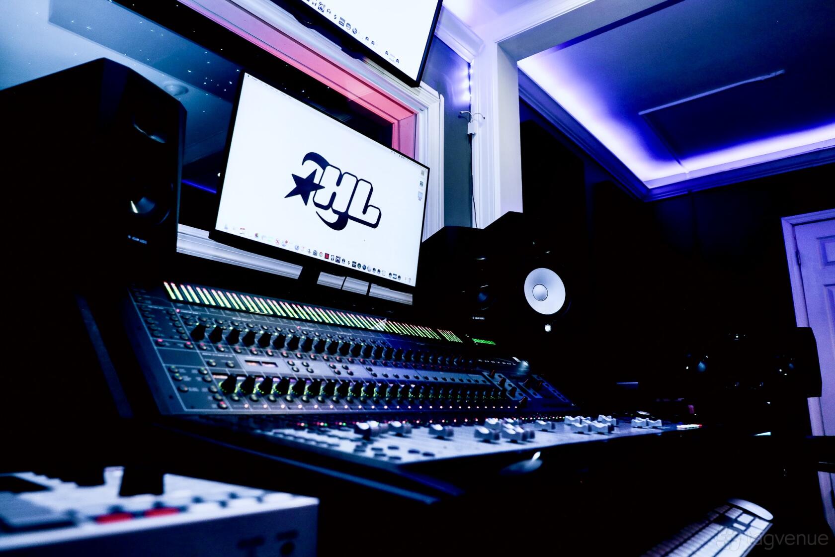 A recording studio with a digital mixing console, studio monitors, and ambient blue lighting at HighLife Studios DC.