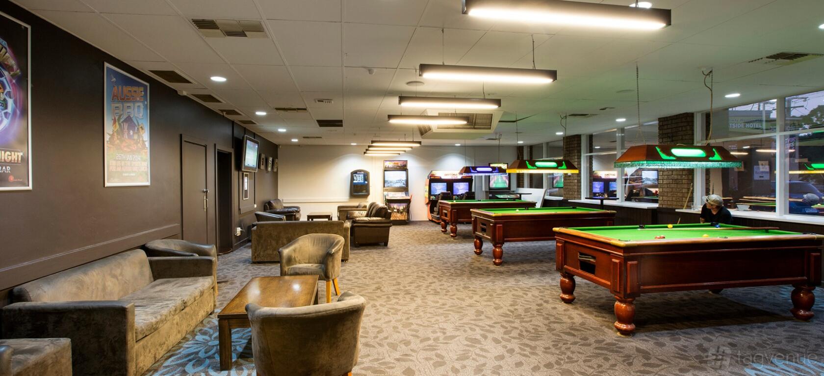 A function room with pool tables, arcade games, and plush seating at Westside Hotel.