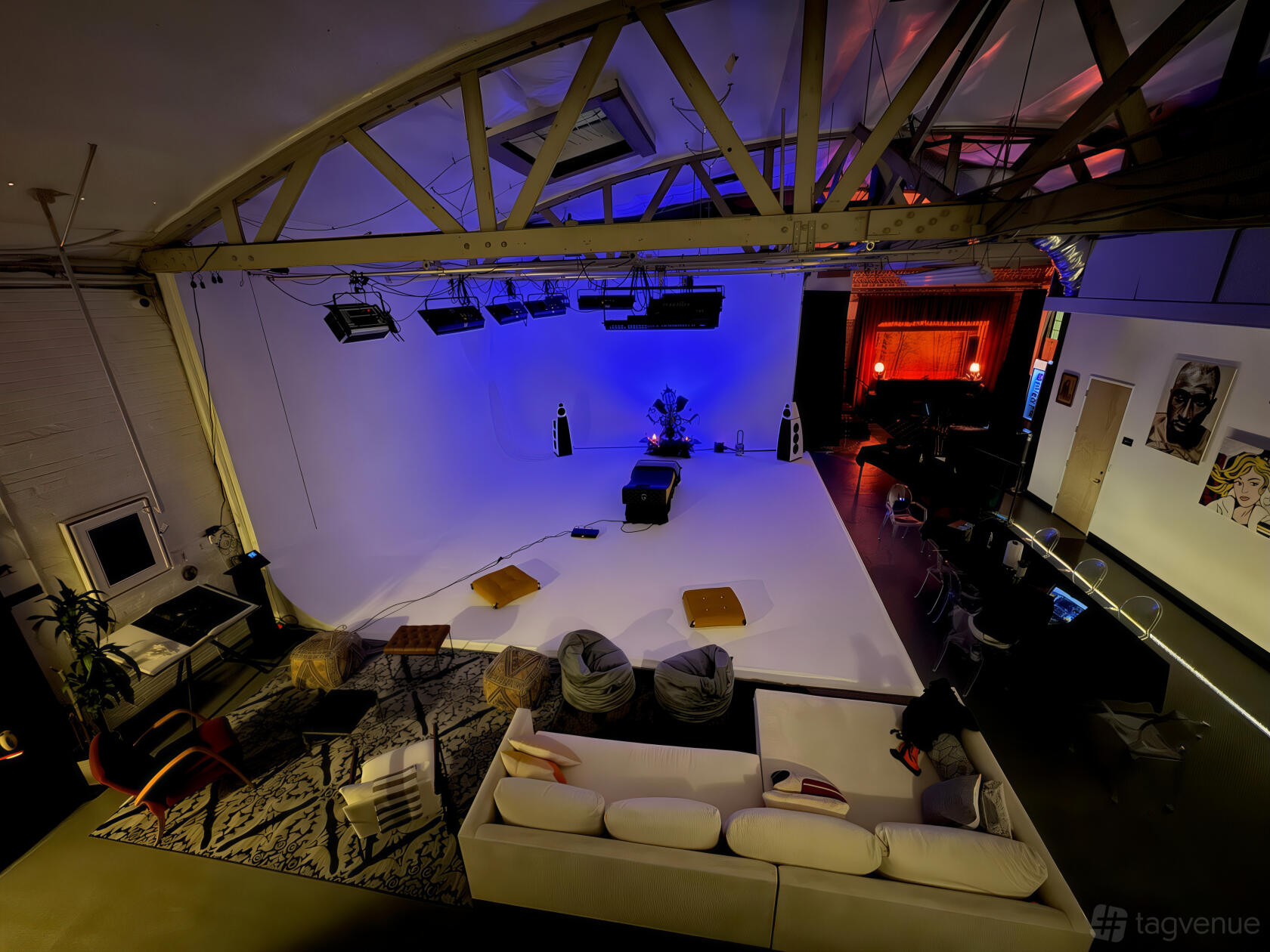 A photo studio with white cyclorama, exposed beams, studio lighting, and lounge seating at Los Angeles Filmmaker Club.