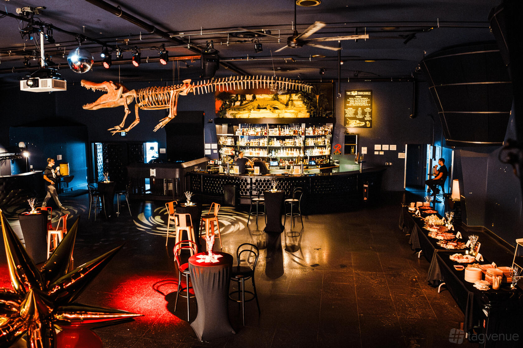 A live music venue with a central bar, high tables, and a dinosaur skeleton installation at The Crocodile.