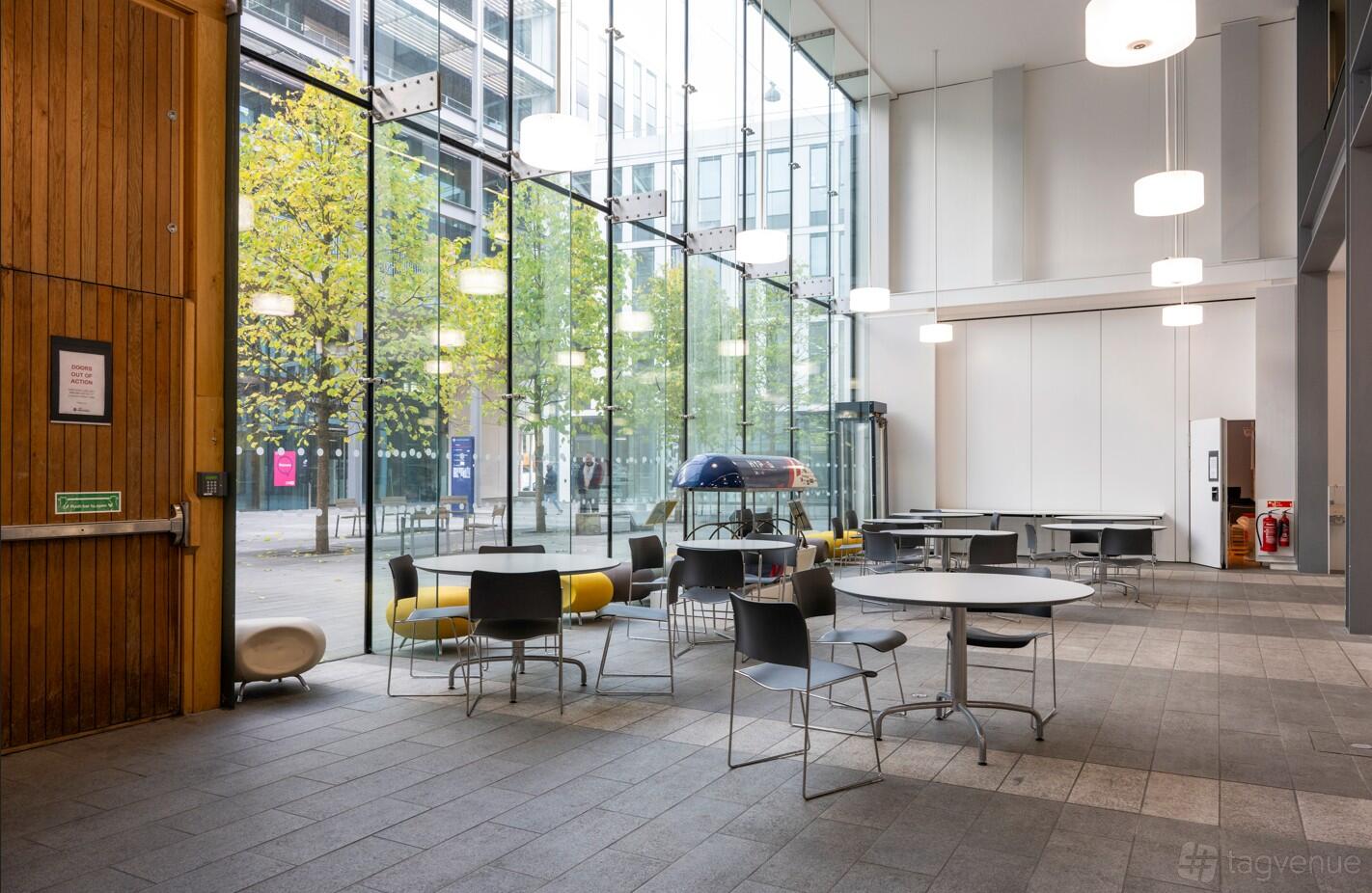 An event space with floor-to-ceiling glass walls, modern pendant lights, and mixed seating at Informatics Forum.