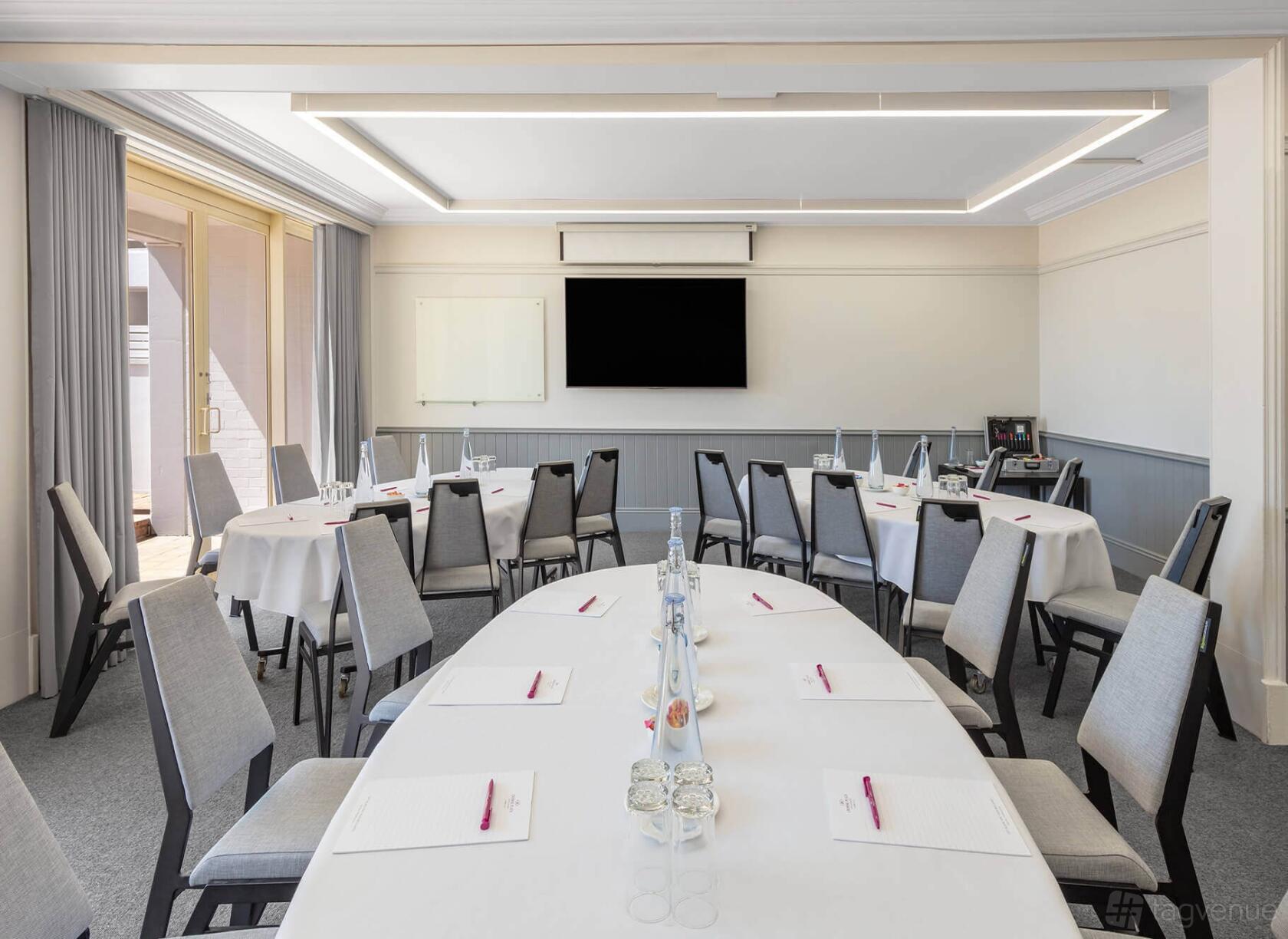 An event space with round tables, grey chairs, and large screen display at Crowne Plaza Terrigal Pacific