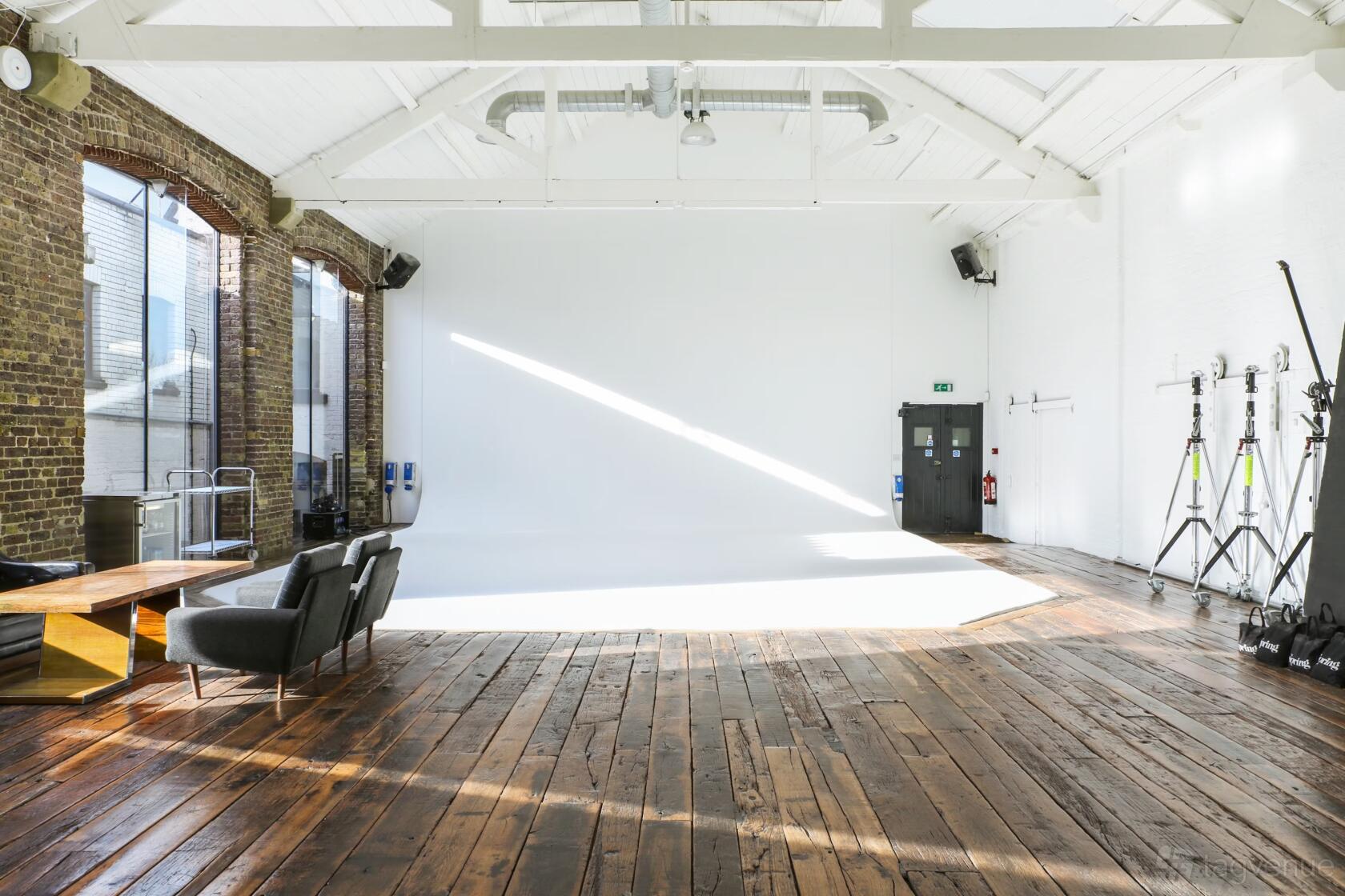 A blank canvas warehouse with exposed brick walls, high white ceilings, and wooden floors at Spring Studios London.