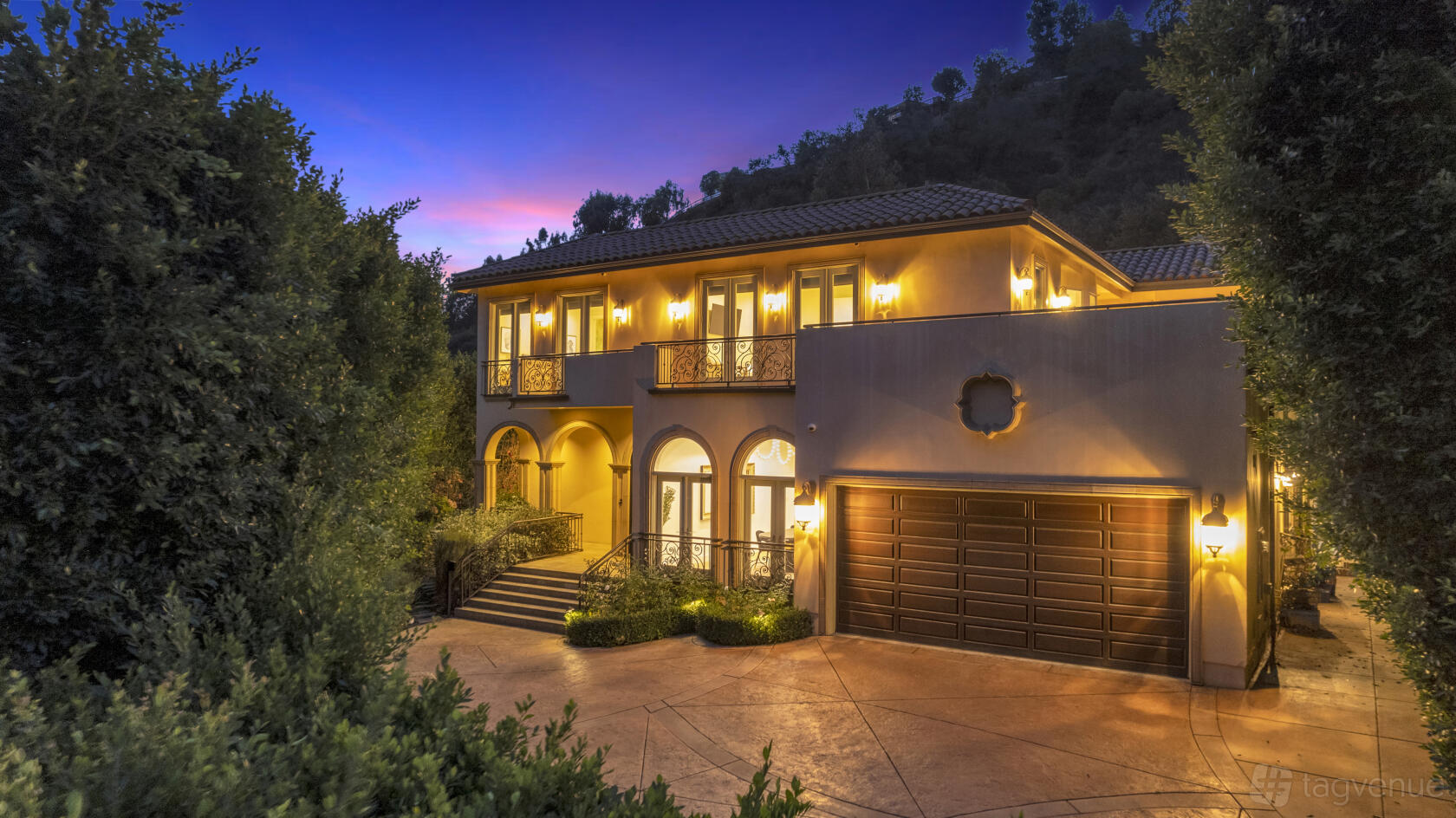 An apartment with arched entryways, wrought iron balconies, and warm exterior lighting at Gated Oasis w/ Resort-Style Pool & Fire Pit.