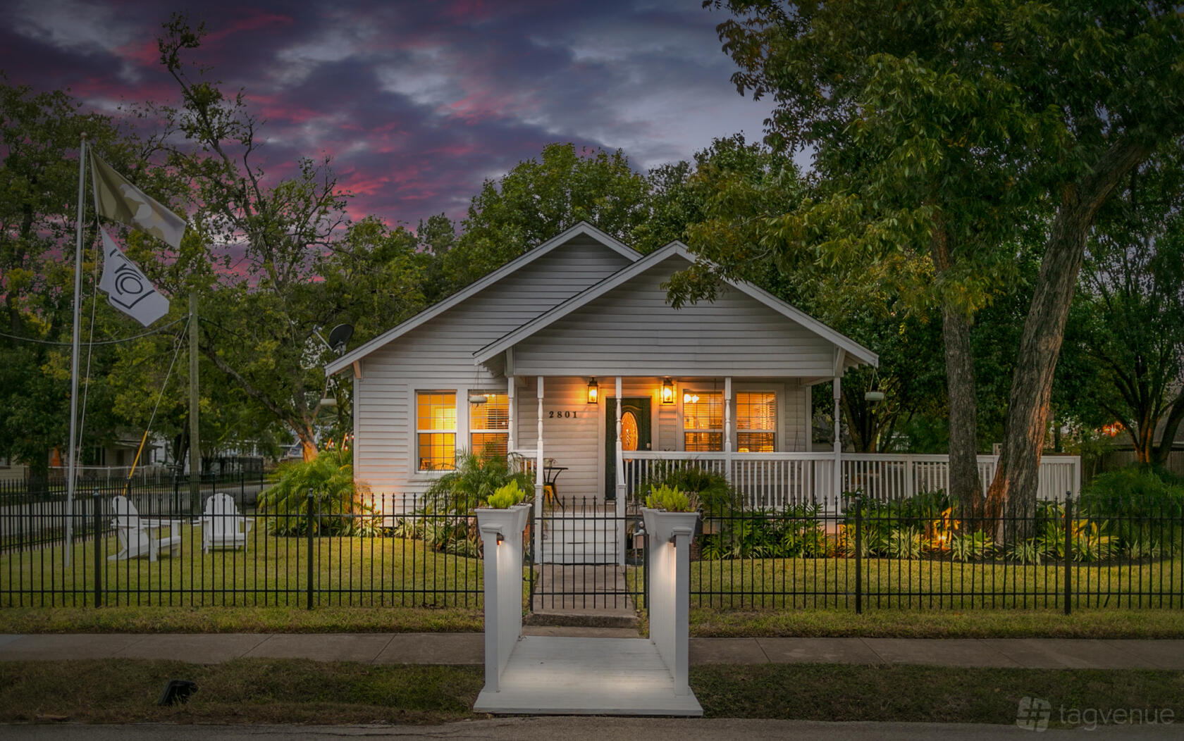 A one-story event venue with a wraparound porch, white fence, and lawn at The Cochran Oriental.