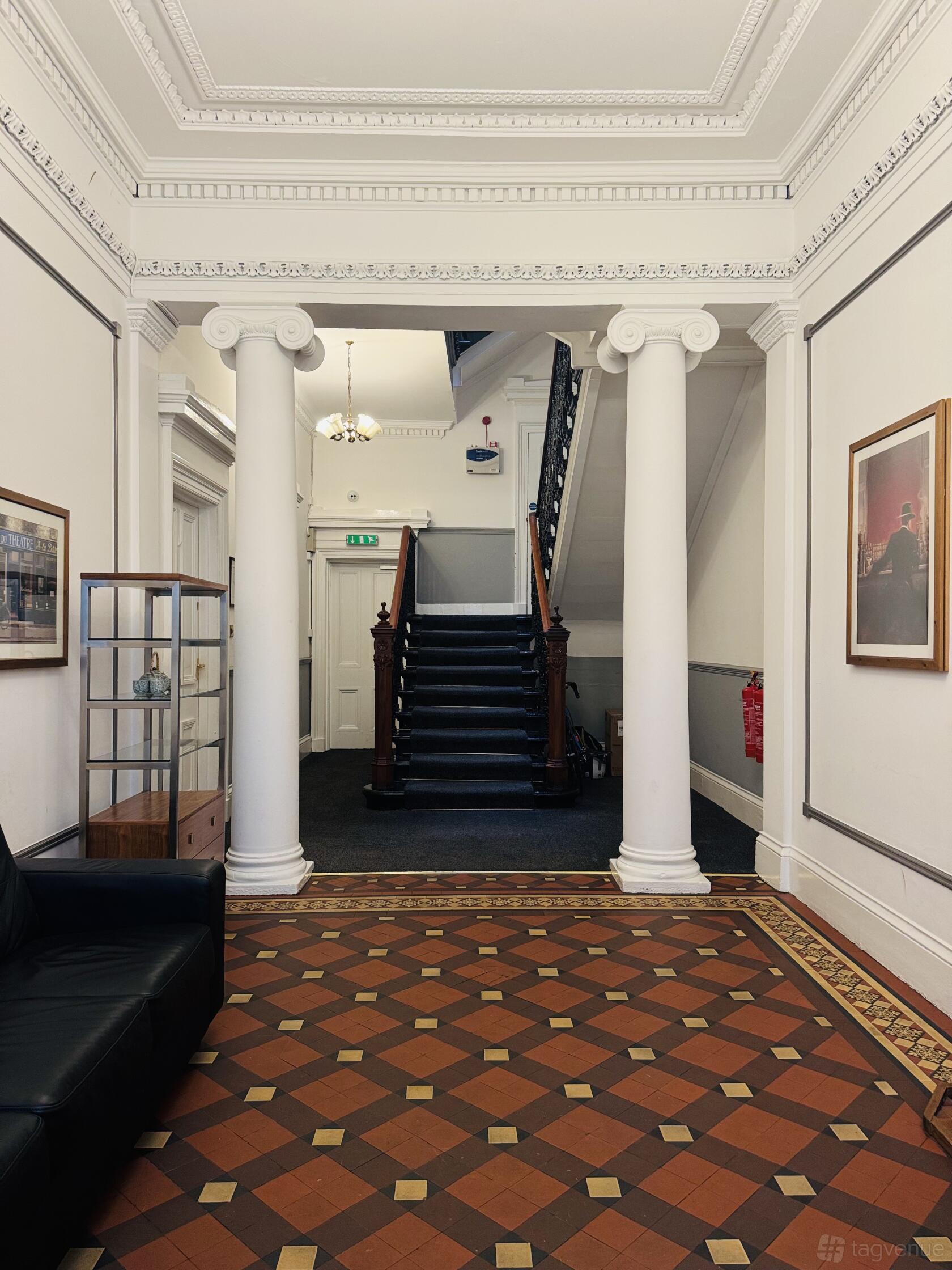 A film/photo studio with a tiled floor, white columns, and a central staircase at Woodside Studios.