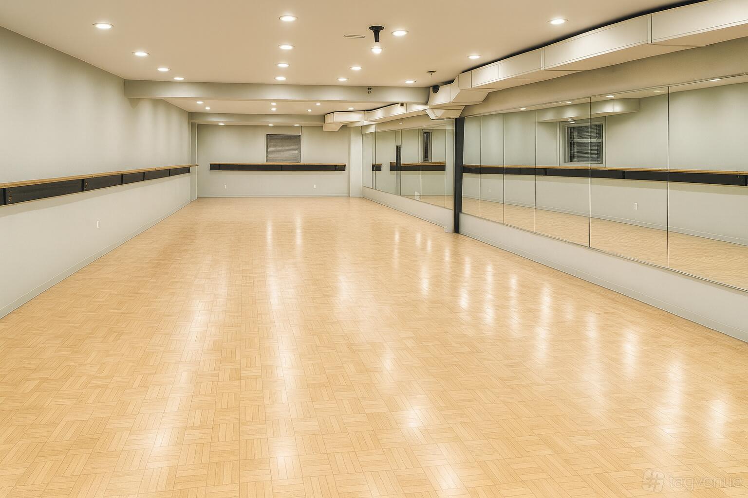 A dance studio with parquet flooring, wall-mounted mirrors, and barre along one wall at Conservatory Of Dance & Music.