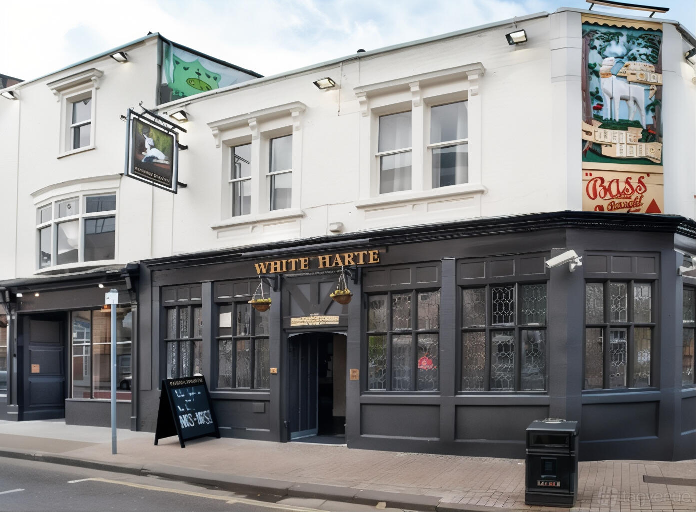 A traditional pub with dark painted facade, leaded glass windows, and hanging signage at The White Harte Bristol.