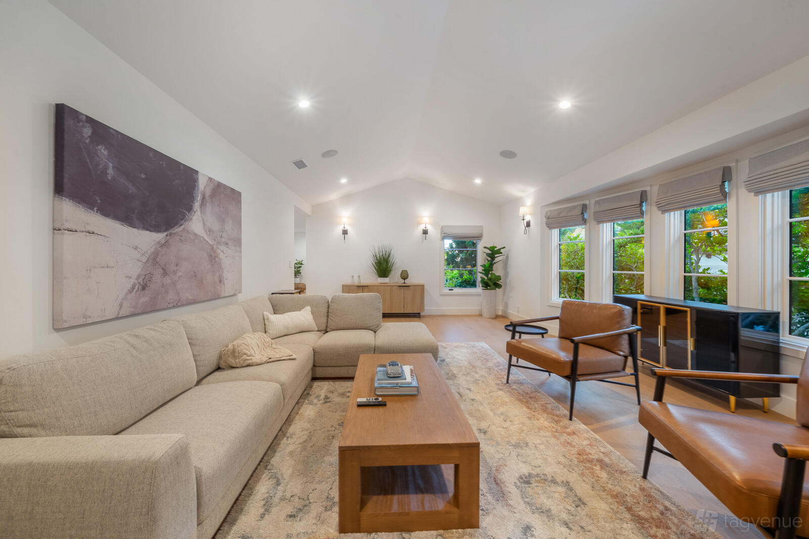 A house living room with vaulted ceilings, neutral furnishings, and large windows overlooking greenery at Hollywood Hills Retreat.