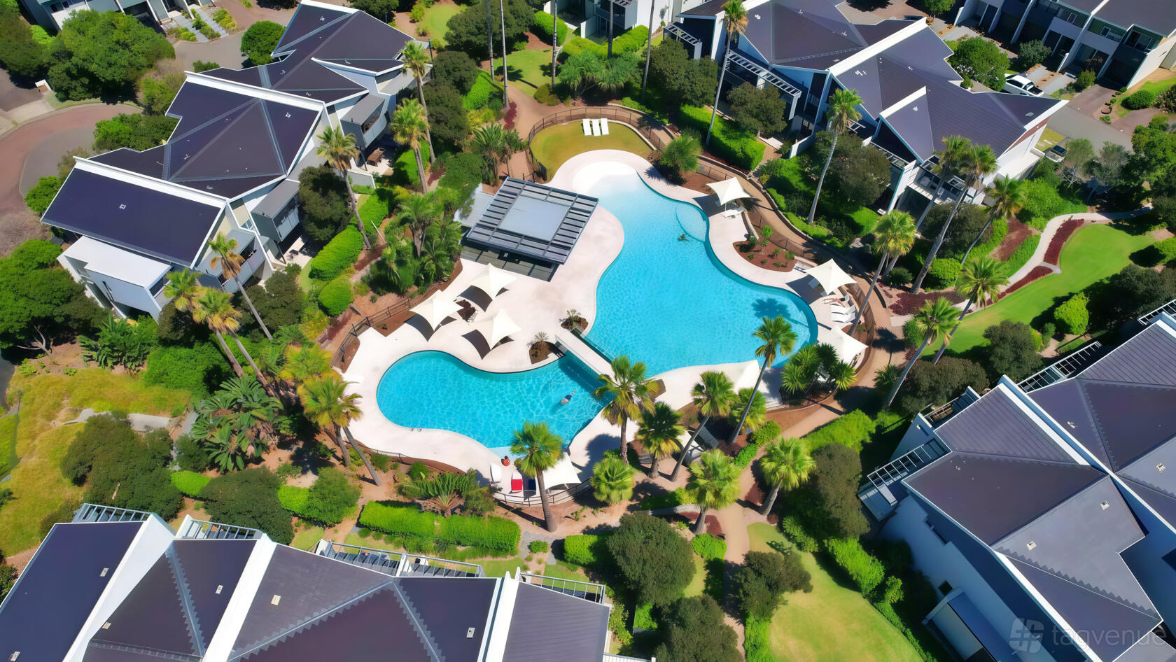 A hotel with a large lagoon-style outdoor pool surrounded by sun loungers, palm trees, and landscaped gardens at Pullman Magenta Shores Resort.