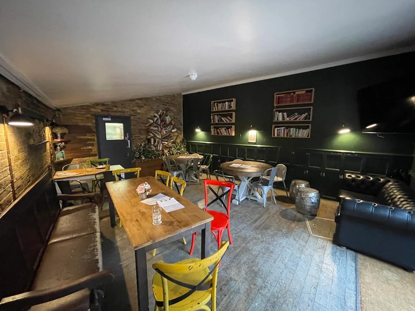 An event space in a pub with exposed brick walls, eclectic chairs, bookshelves, and a leather sofa at The William Morris.