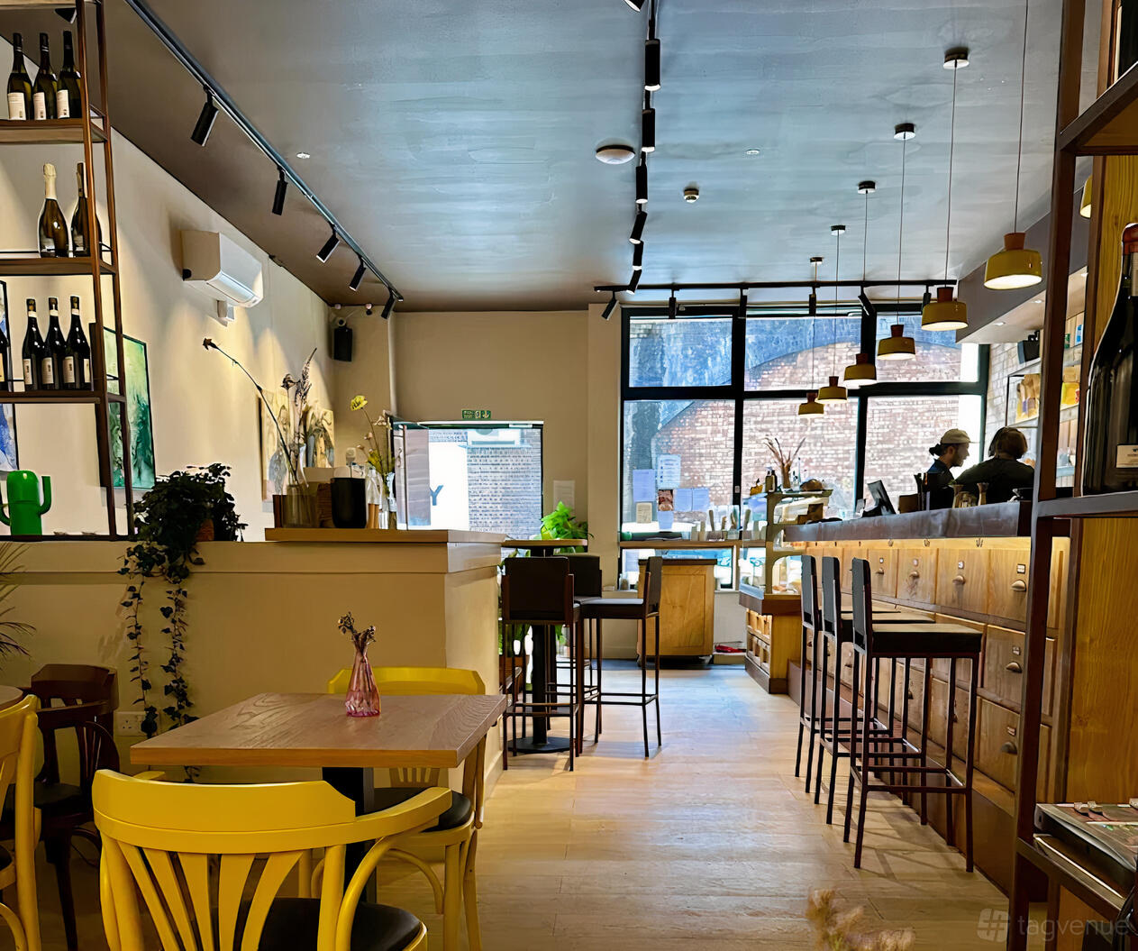 A cafe with natural lighting, wooden tables, high stools, and hanging pendant lights at Malavenda Cafè & Bistro.