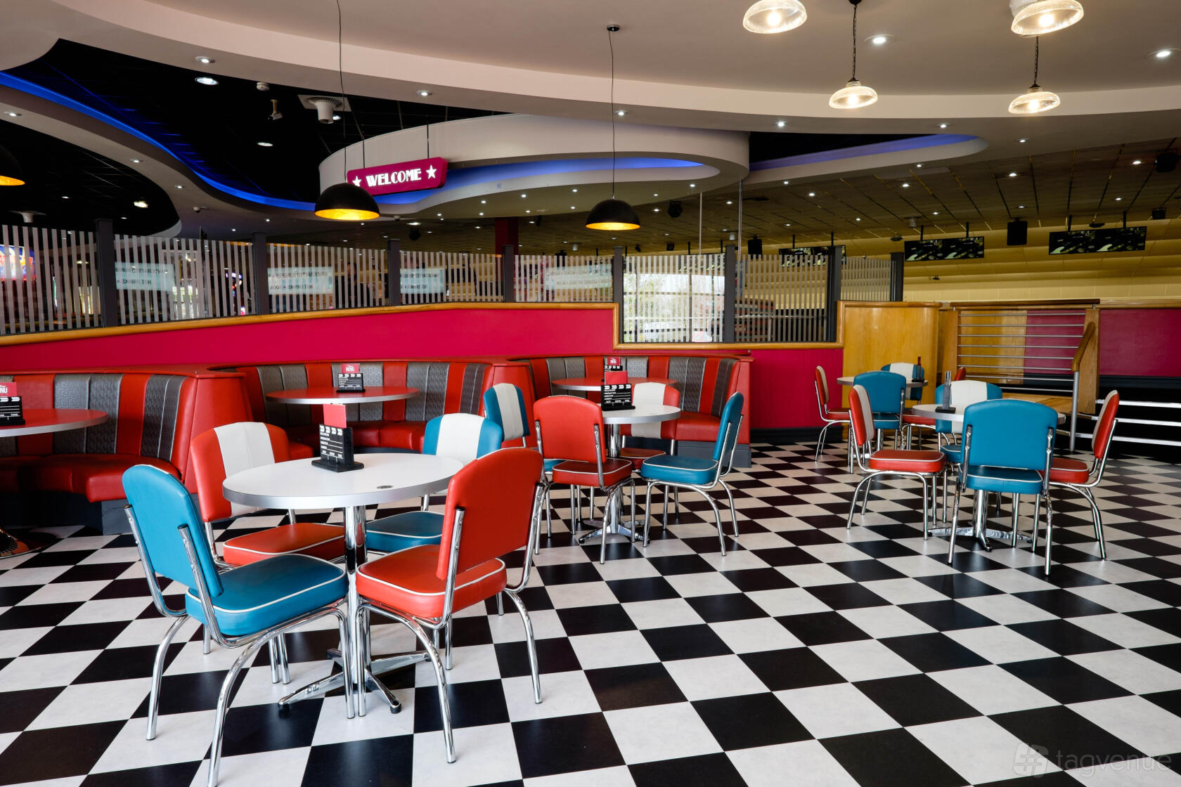 A bowling alley with retro diner seating, checkered flooring, and bold colored booths at Hollywood Bowl Birmingham Rubery.