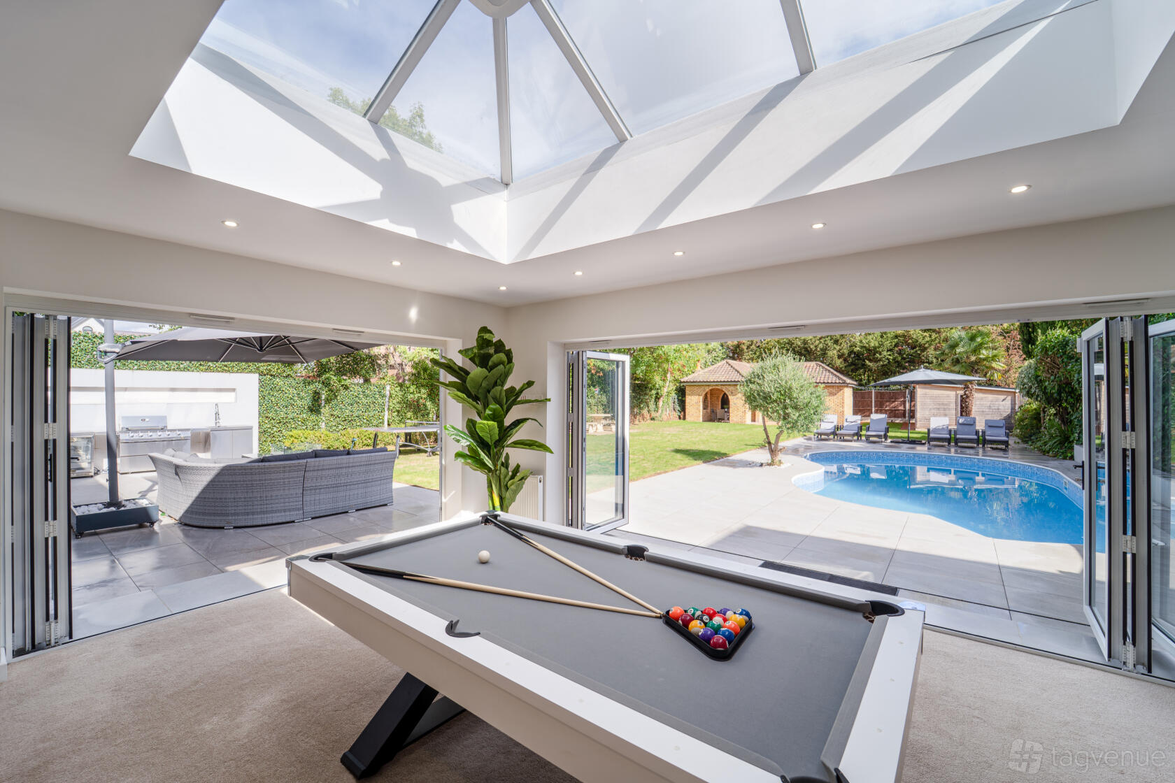 A house with a skylit game room, pool table, and sliding doors opening to a patio, pool, and garden at Emerson Park Villa.