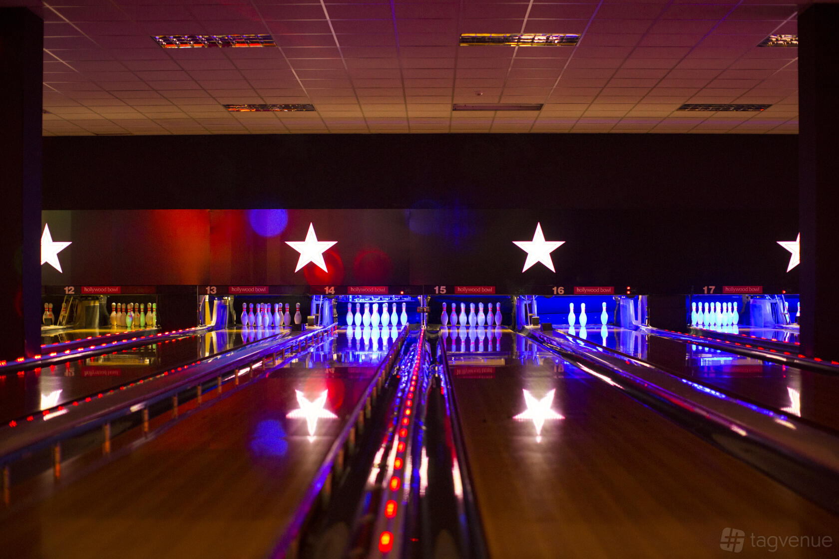 A bowling alley with illuminated lanes, glowing pins, and star-shaped wall lights at Hollywood Bowl Birmingham Broadway Plaza.