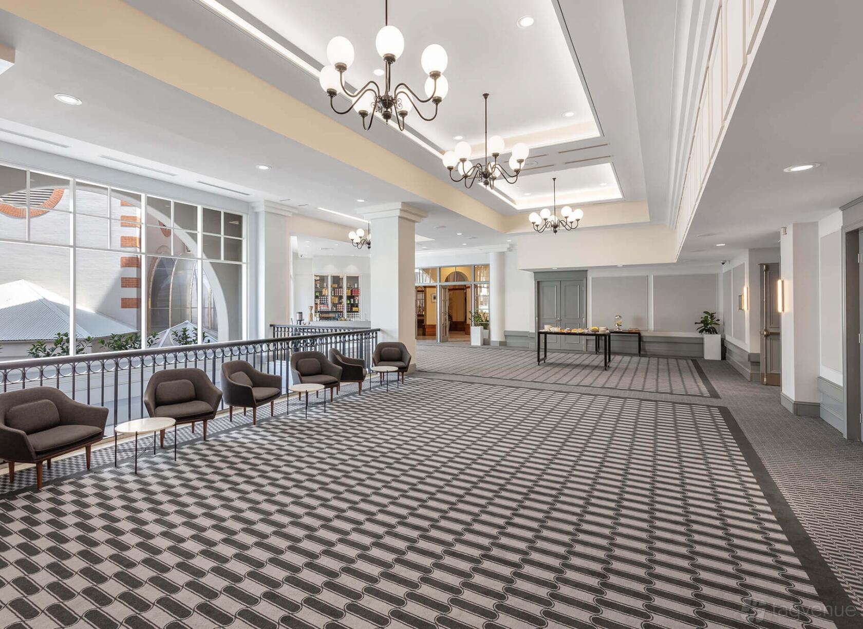An event space in a hotel with patterned carpeting, lounge seating, chandeliers, and large windows at Crowne Plaza Terrigal Pacific.