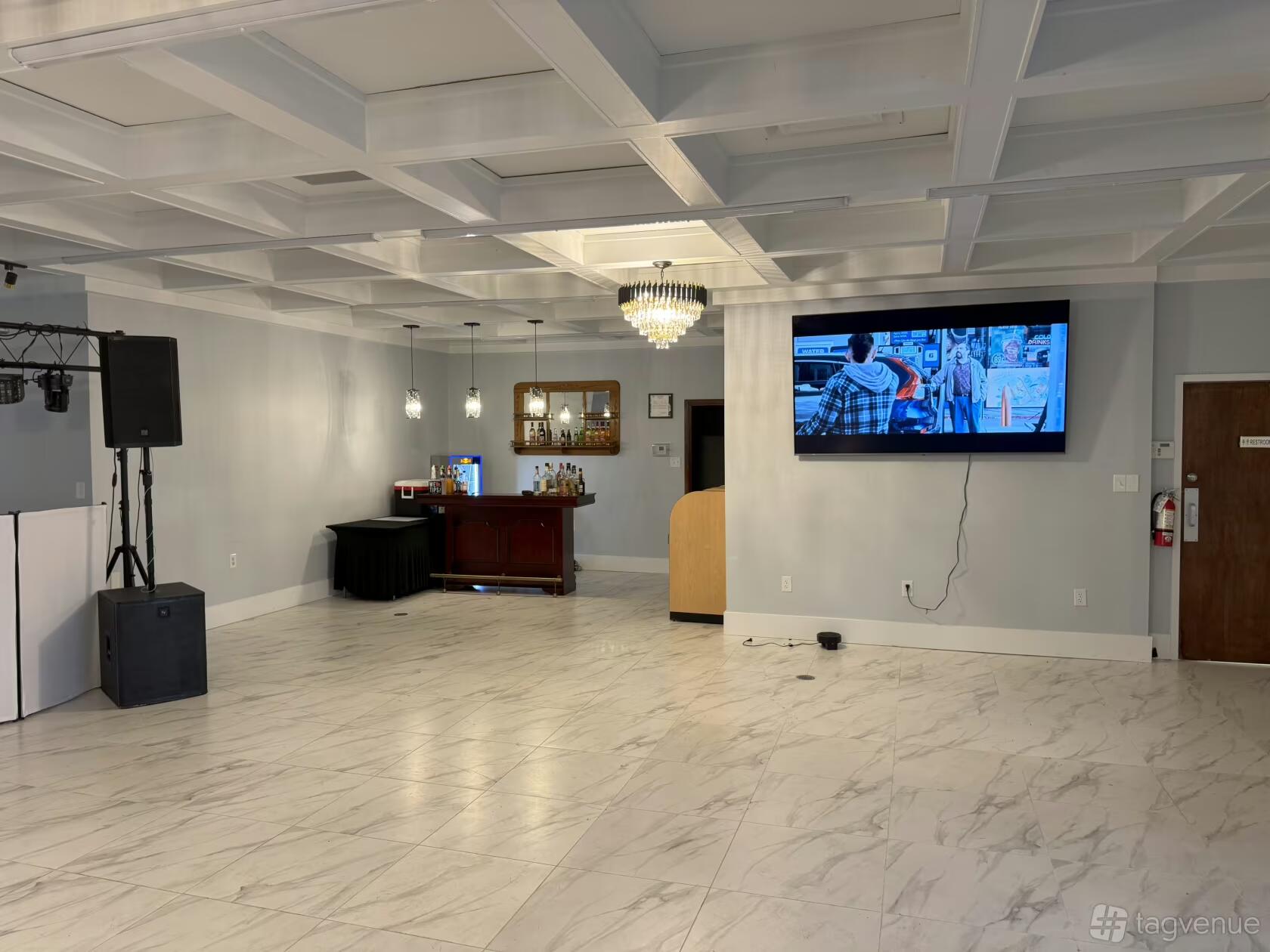 An event hall with marble floors, a chandelier, wall-mounted TV, and a small bar counter at CHARLO EVENT CENTER.
