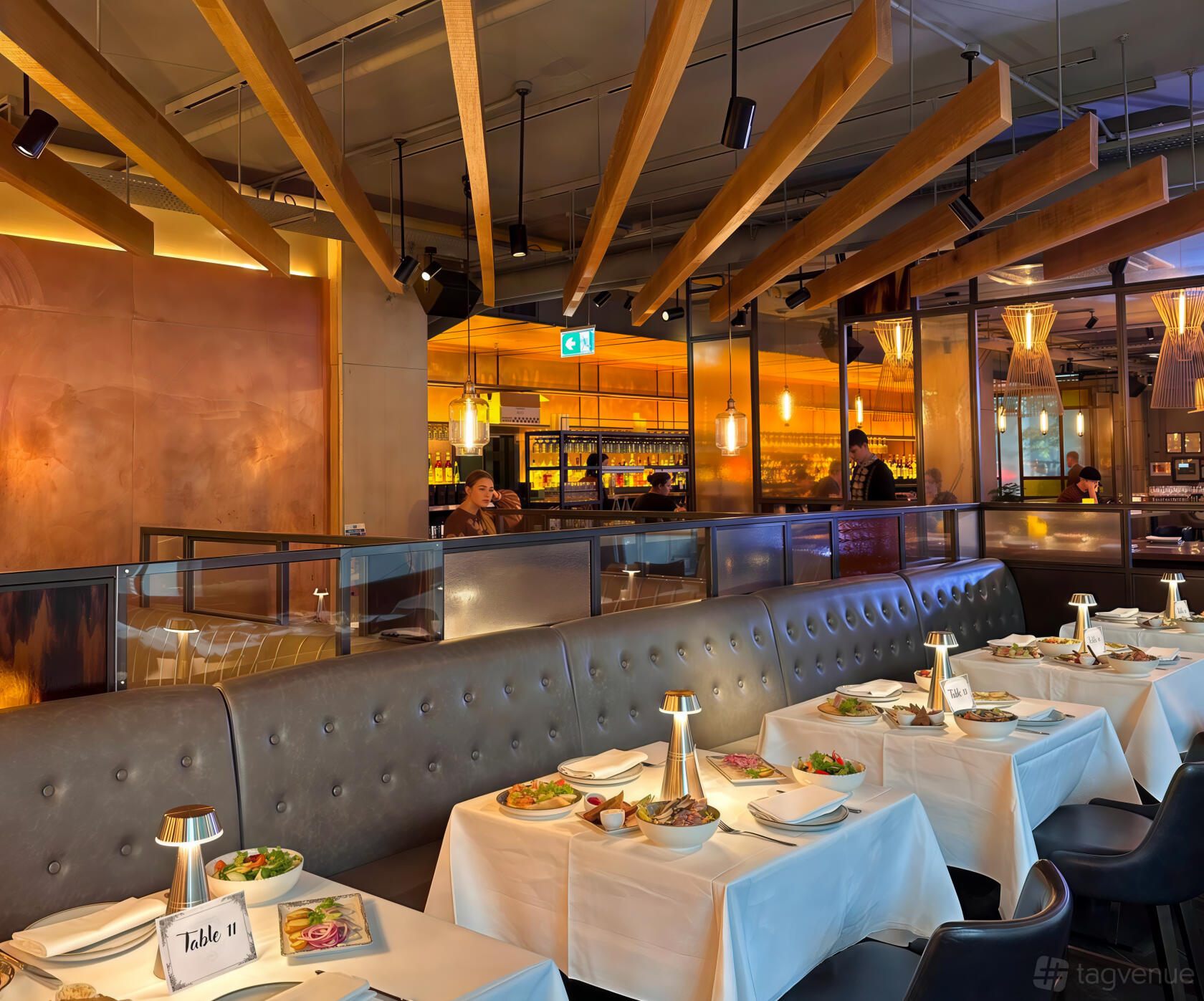 A restaurant with a tufted banquette, exposed wood ceiling beams, and white tablecloths at Ole Kyiv Old Street.