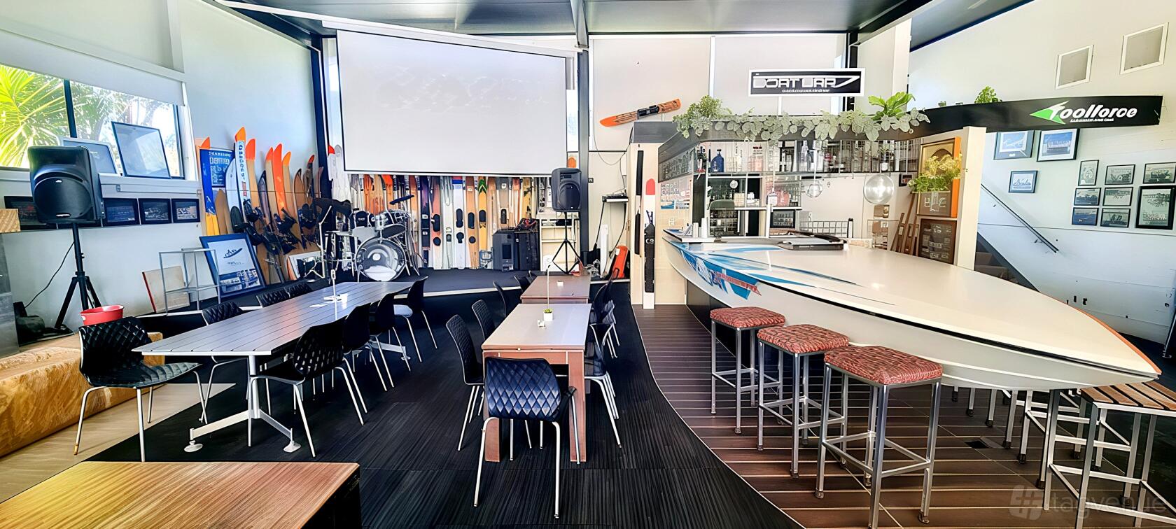 A cafe with surfboards lined along the wall, a stage with musical instruments, and a bar counter at Paradise Cafe.
