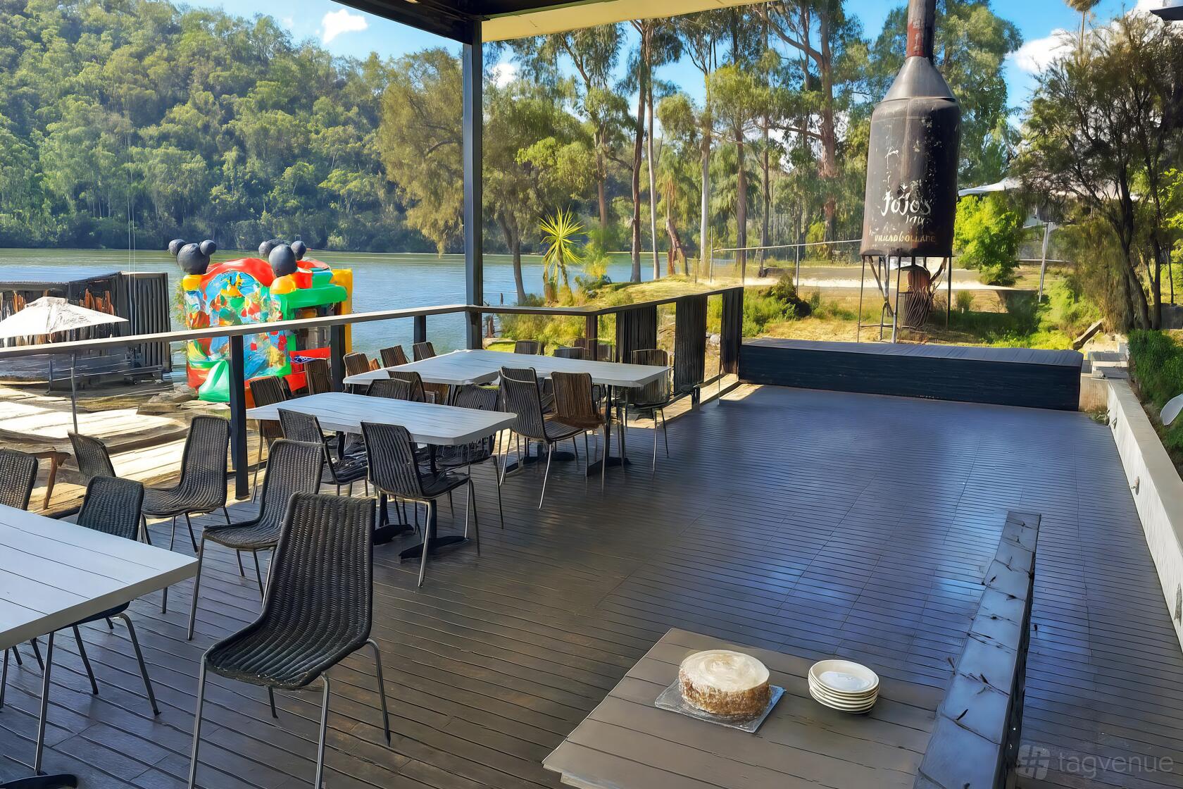 An outdoor dining area with metal chairs, light wood tables, and river views at Paradise Cafe.