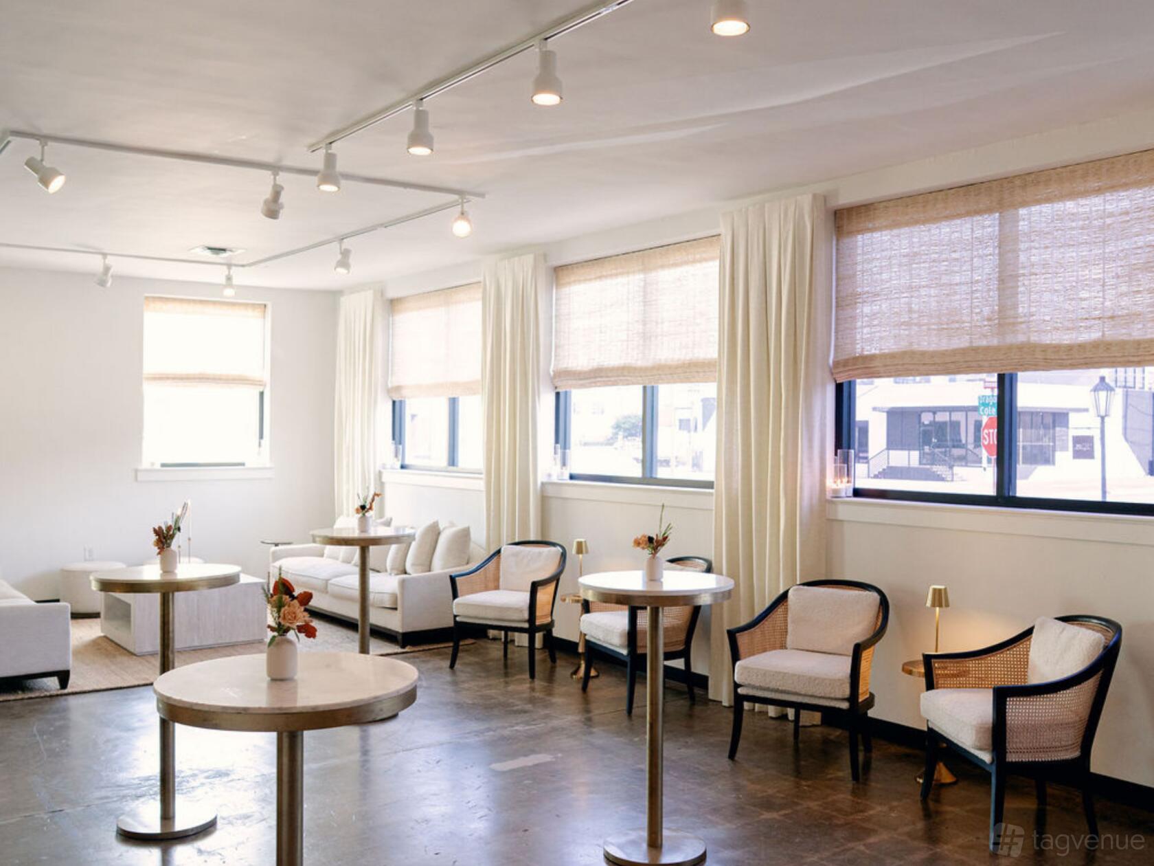 A dining room with round tables, white armchairs, and large windows with sheer curtains at Room 1403.