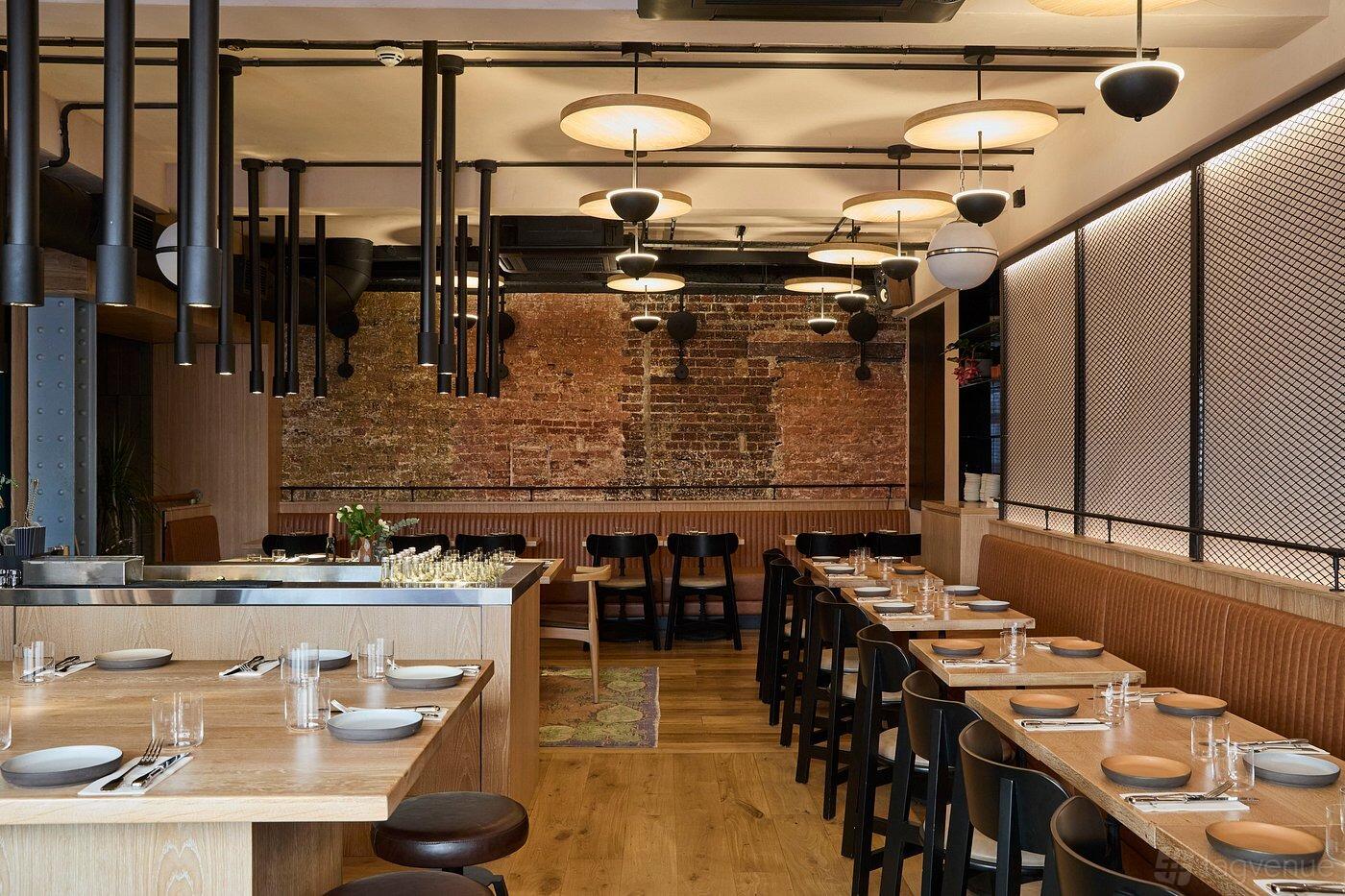 A restaurant with exposed brick walls, wooden tables set with glassware, and pendant lighting at The Counter.