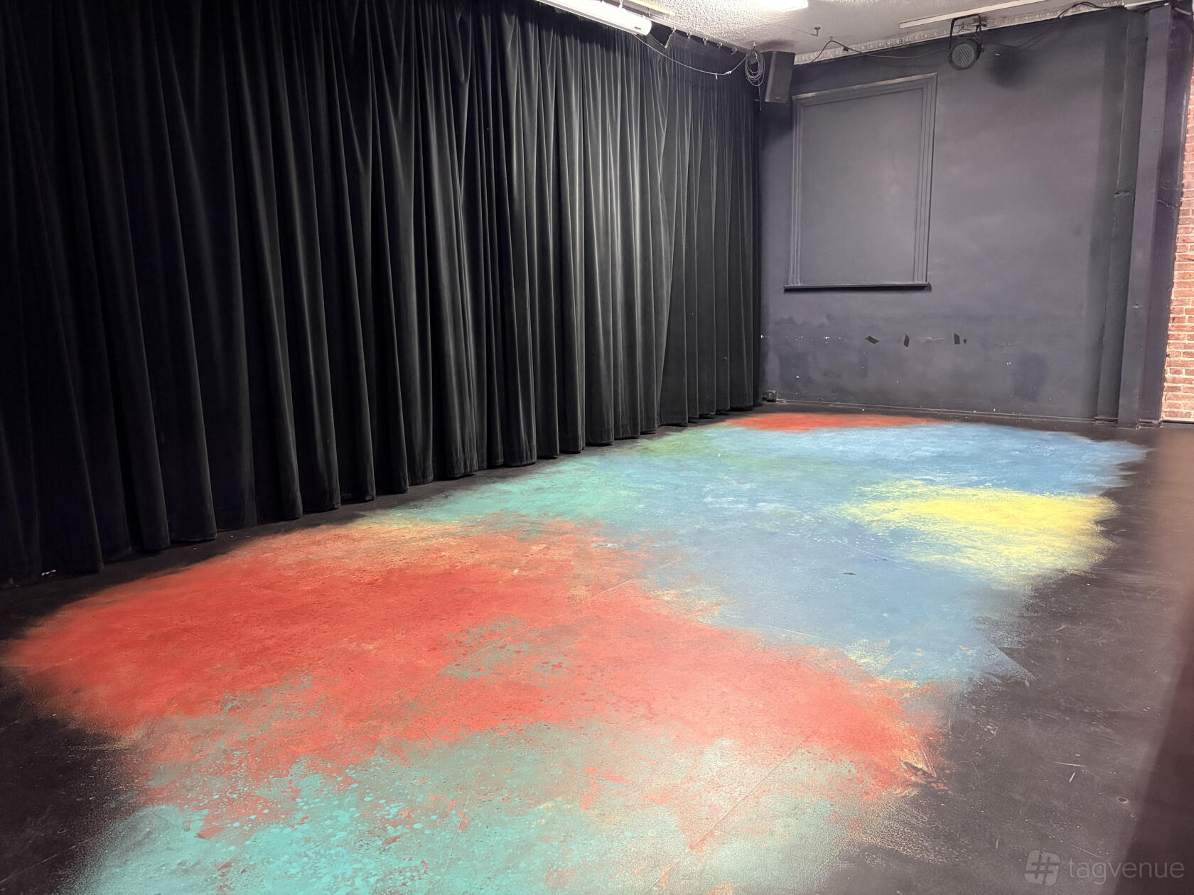 A creative studio with black curtains and a floor painted in red, blue, and yellow at The Noho Actor's Studio.