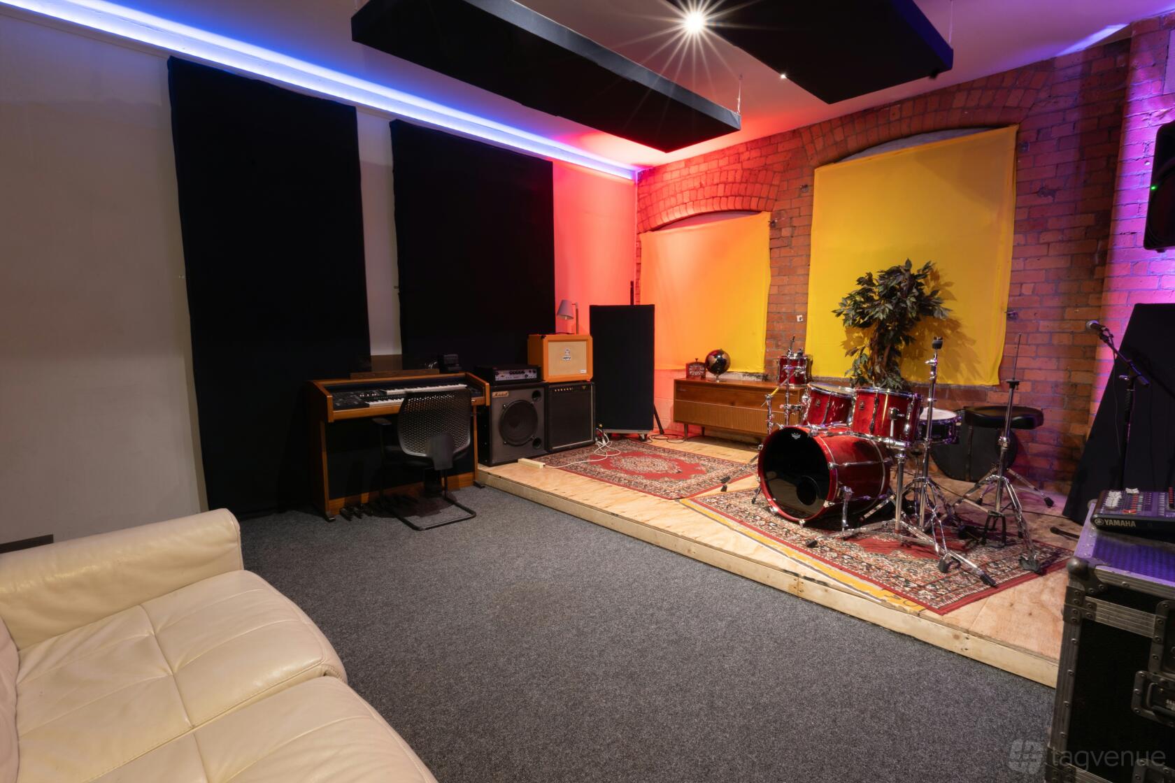 Studio 3 at Habitat Studios with exposed brick wall, drum kit, keyboard, and acoustic panels