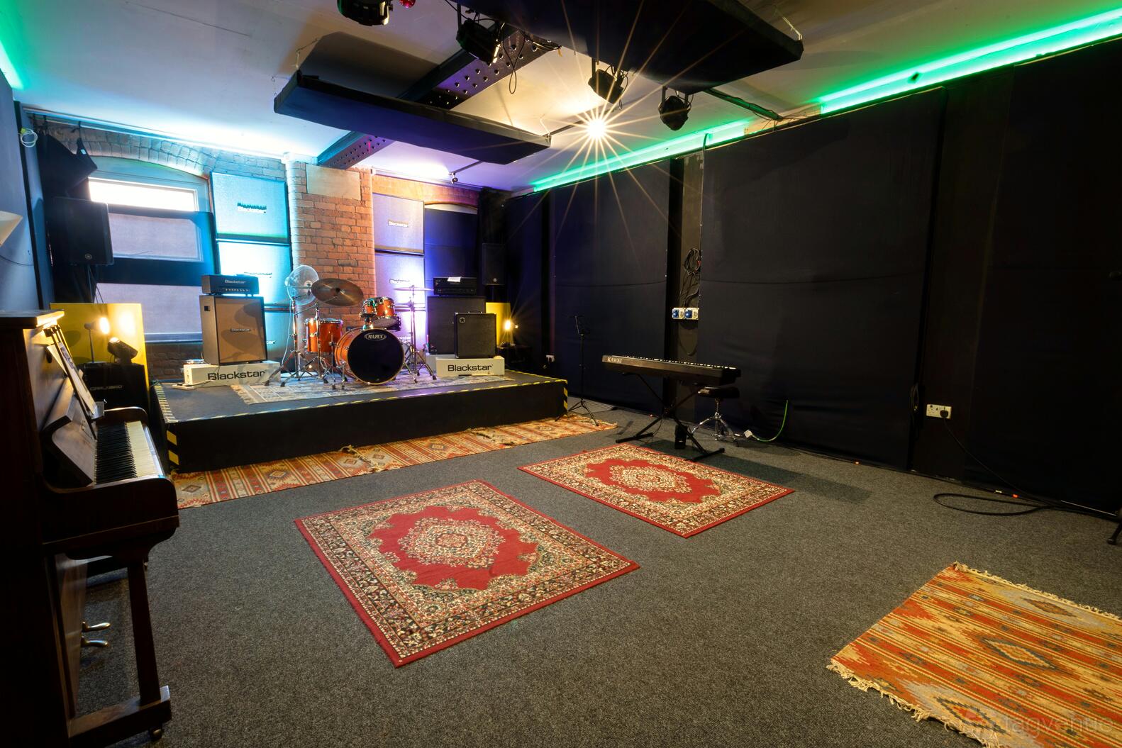 Studio 2 at Habitat Studios with drum kit, amps, piano, and colorful rugs