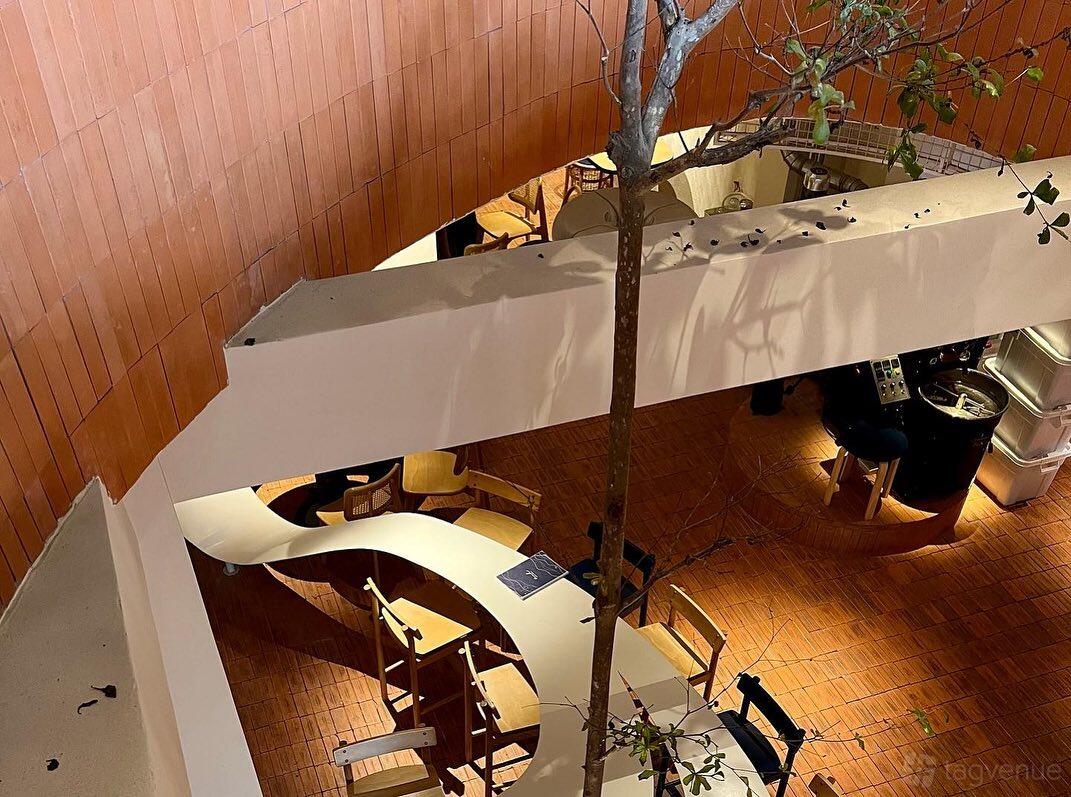 A restaurant with curved communal tables, wooden chairs, and terracotta tiled floors at Little Green Cyclo.