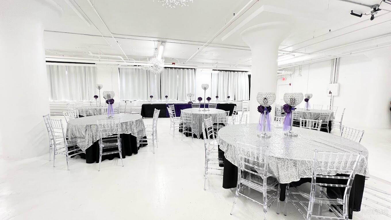 An event venue with round tables covered in silver linens, chiavari chairs, and crystal centerpieces at Vanilla Skies Event Spaces.