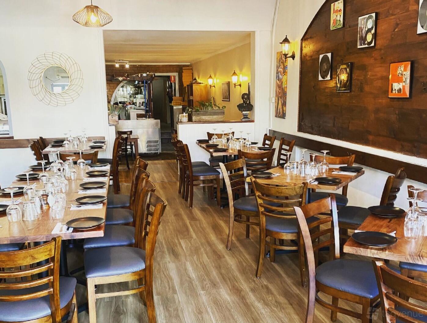 A restaurant with wooden tables, matching chairs, and wall art on a wood-paneled accent wall at 7ettimo ristorante.
