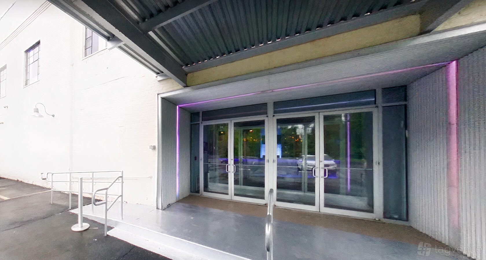 A hall entrance with double glass doors, covered metal awning, and accessible ramp at LIFE The Place To Be.
