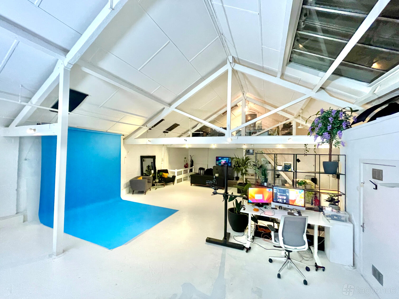 A photo and film studio with a blue backdrop, high ceilings, and workstations at Motherlight Studios.