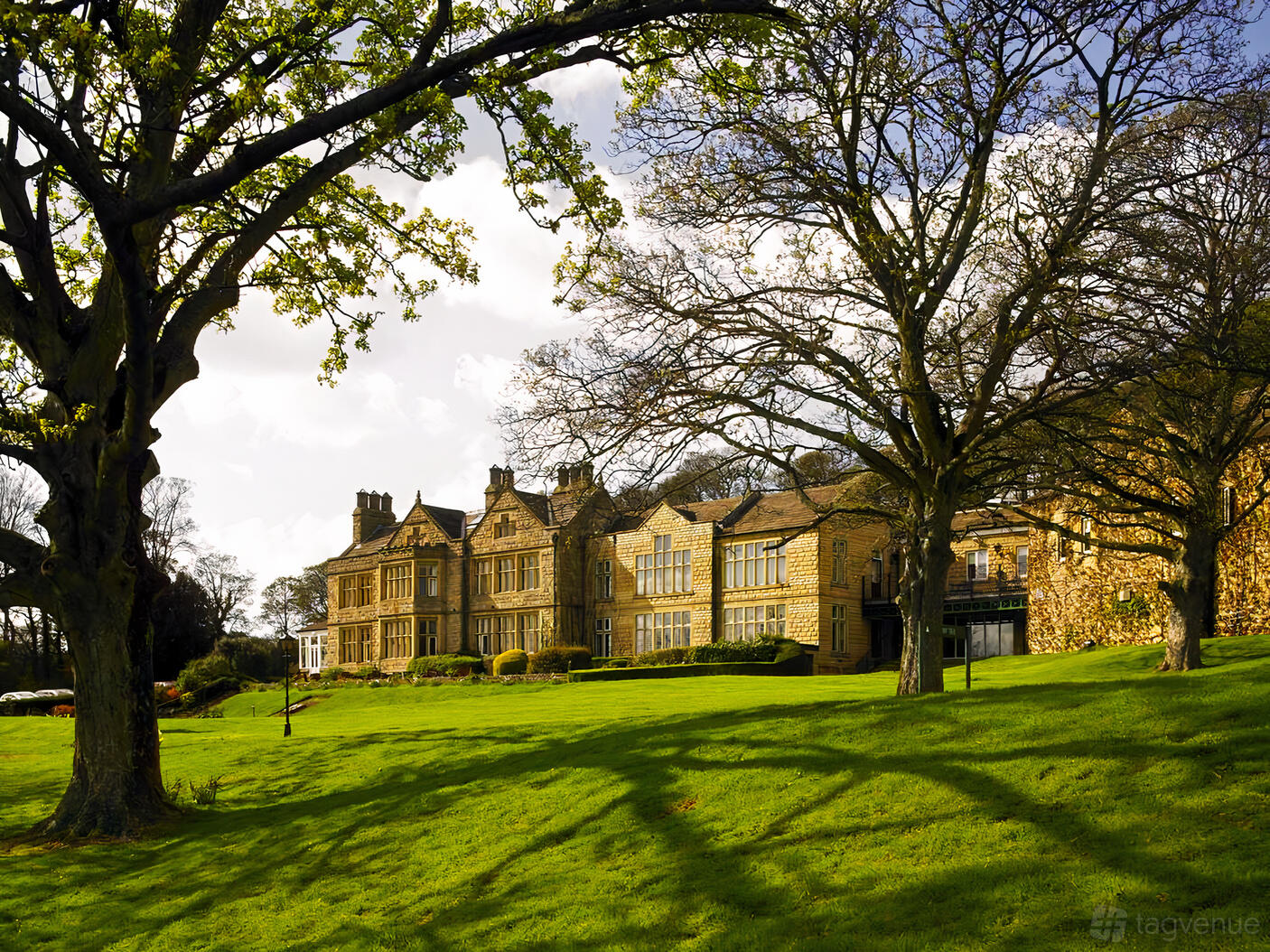 A historic hotel with a stone facade, large windows, and manicured lawns at Hollins Hall Hotel, Golf & Country Club.