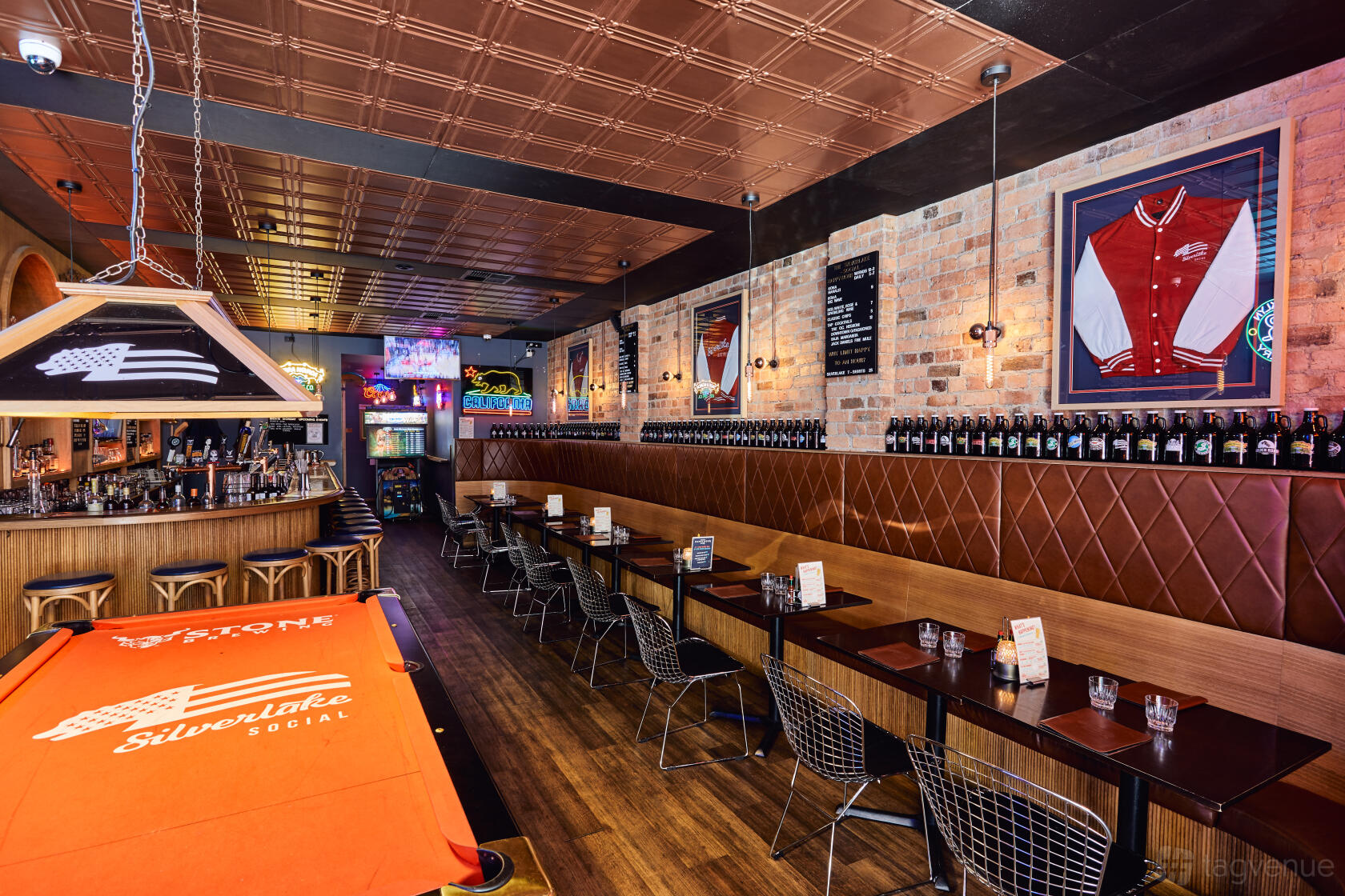 A restaurant with exposed brick walls, wooden flooring, and a billiards table at Silverlake Social.