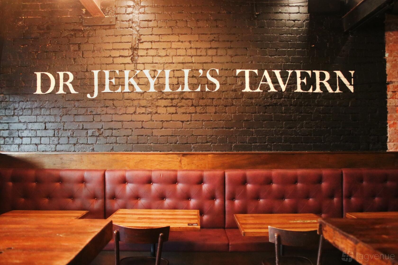 An event space in a bar with tufted leather banquettes, dark wood tables, and a brick wall at Jekyll & Hyde.
