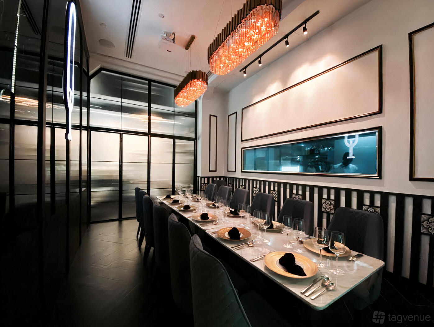 A private dining room with a long marble table, black upholstered chairs, and modern chandeliers at Quentin's Bar and Restaurant.
