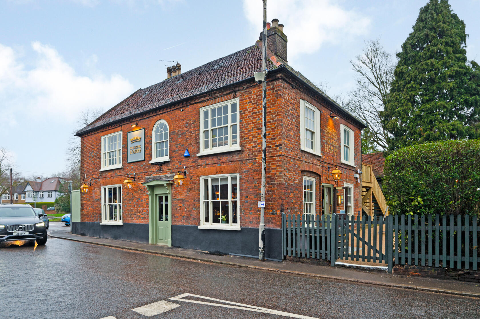 A traditional brick pub with sash windows, green doors, and exterior signage at The King Harry.