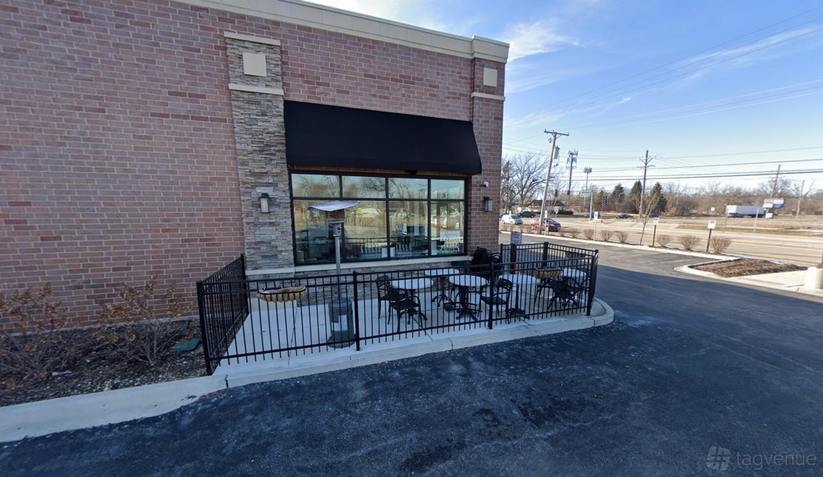 An outdoor patio with black metal chairs, tables, and a tall heater at Rosario's Pizzeria & Catering.
